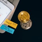 Bitcoin coins and smartphone displaying price chart with investment notes.