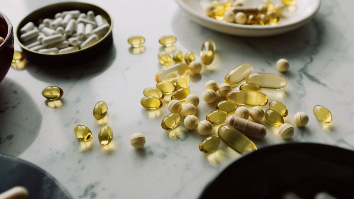 A close-up of assorted pills and supplements arranged on a marble surface, highlighting healthcare and wellness themes.