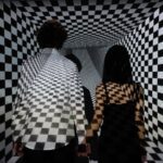 illuseum berlin - Couple walking in a checkerboard tunnel, creating an optical illusion of depth and