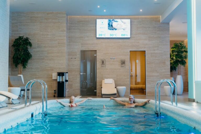mediterana - Two adults enjoying leisure time at an indoor swimming pool with spa-like ambiance.