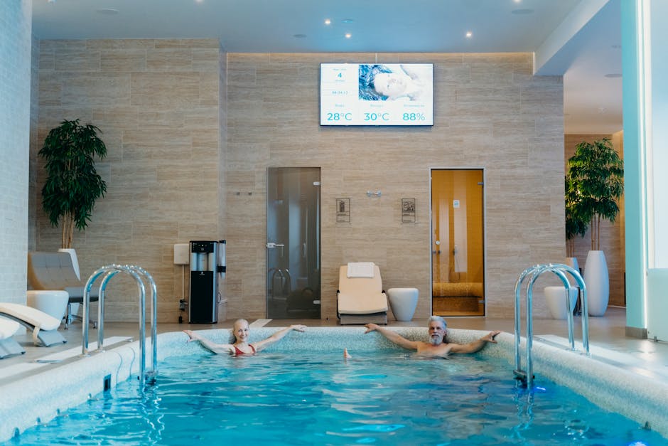 mediterana - Two adults enjoying leisure time at an indoor swimming pool with spa-like ambiance.