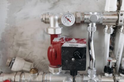 selfio - Close-up view of an industrial plumbing system featuring a pressure gauge and steel pipes.