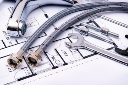 selfio - Close-up of plumbing tools and faucet on top of an architectural blueprint, perfect for har
